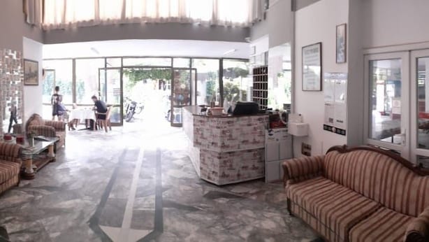 A spacious lobby with striped sofas, a reception desk, and a large window offering a view of the outdoors. - Tecimen Hotel (Kusadasi)