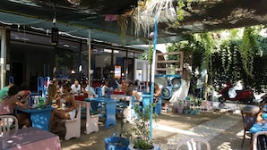 An outdoor café with tables and chairs, surrounded by greenery and potted plants. - Tecimen Hotel (Kusadasi)