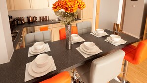A modern kitchen with a dining area. There is a vase with flowers on the table, and the kitchen has a stove and cabinets. - ByEvo 1 Brabloch GLA Apartment  (Paisley)