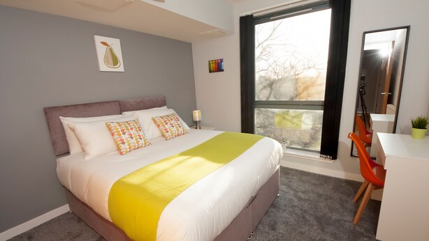 A modern bedroom with a large bed, a desk, and a window with curtains. - ByEvo 1 Brabloch GLA Apartment  (Paisley)