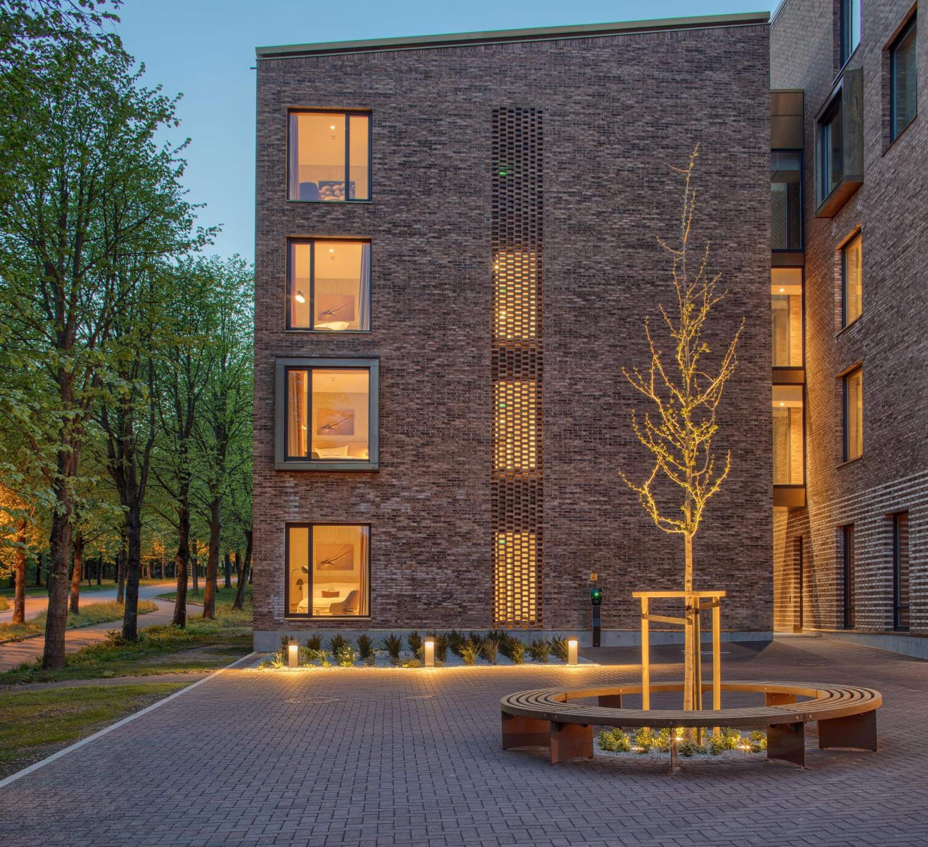 Ein modernes Gebäude mit vielen Fenstern und einem Baum im Innenhof.
