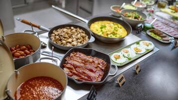 A buffet with various dishes including bacon, mushrooms, and eggs.