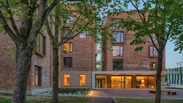 A modern building with a brick facade, large windows, and a well-lit entrance area.