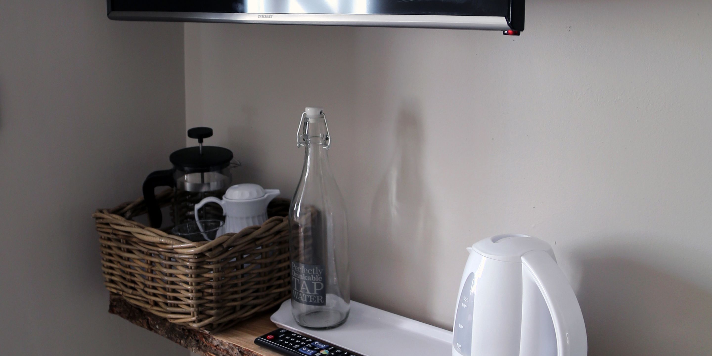A kitchen counter with a coffee maker, a glass bottle, and a basket.
