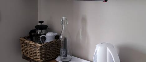 A kitchen counter with a coffee maker, a glass bottle, and a basket.
