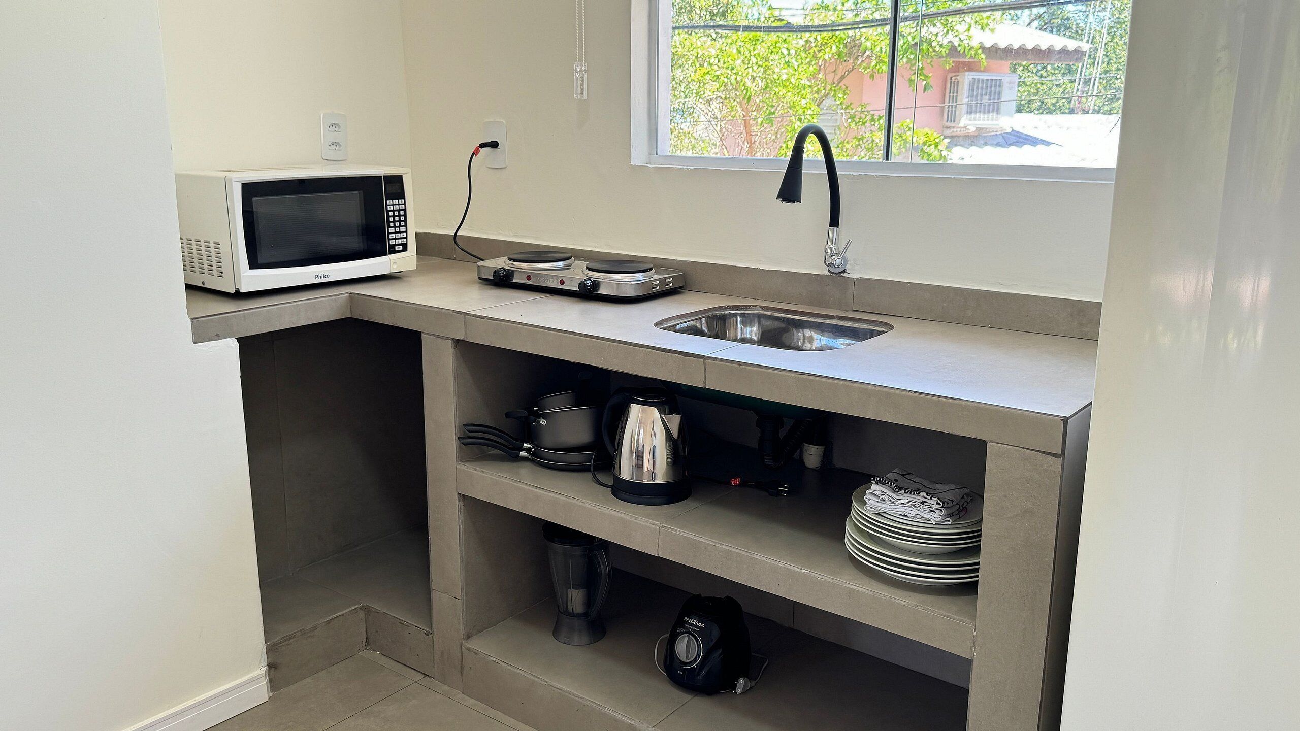 A compact kitchenette with a microwave, sink, and storage shelves.
