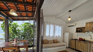 A compact kitchen with a dining area, a sofa, and a view of greenery outside. - Quinta da Margem (Florianópolis)
