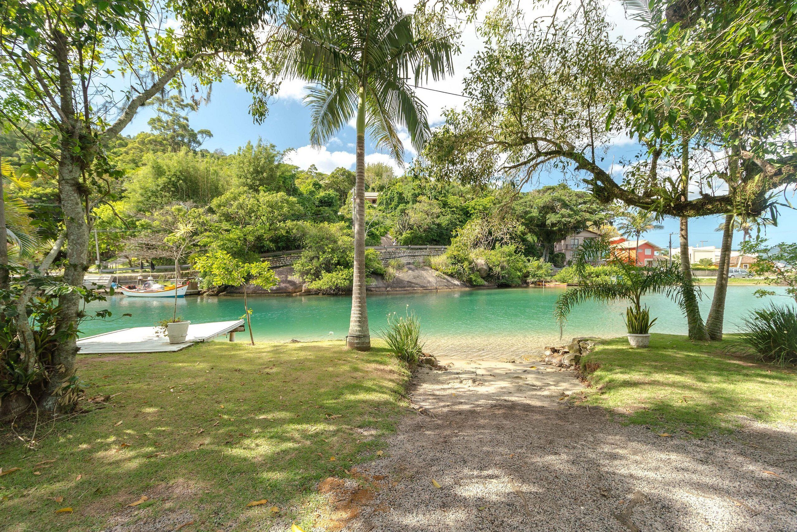 A serene lakeside setting with a dock, boats, and a pathway leading to the water.