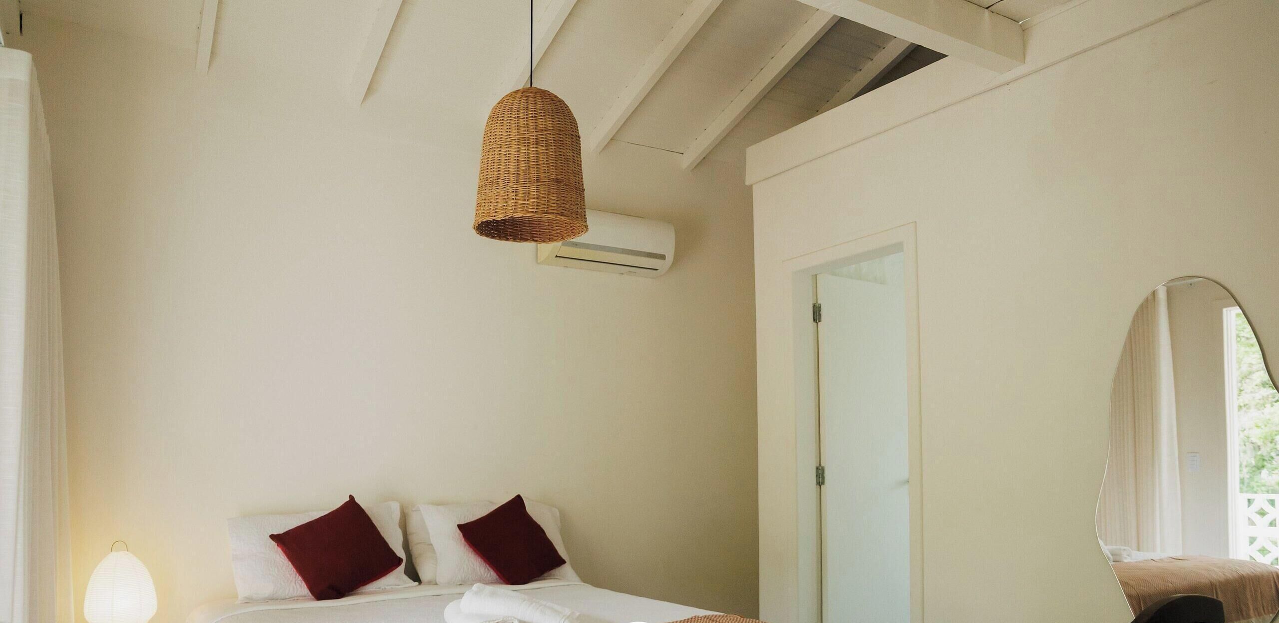 Ein Schlafzimmer mit einem Bett, zwei Kissen, einer Hängelampe, einer Klimaanlage und einer Tür.