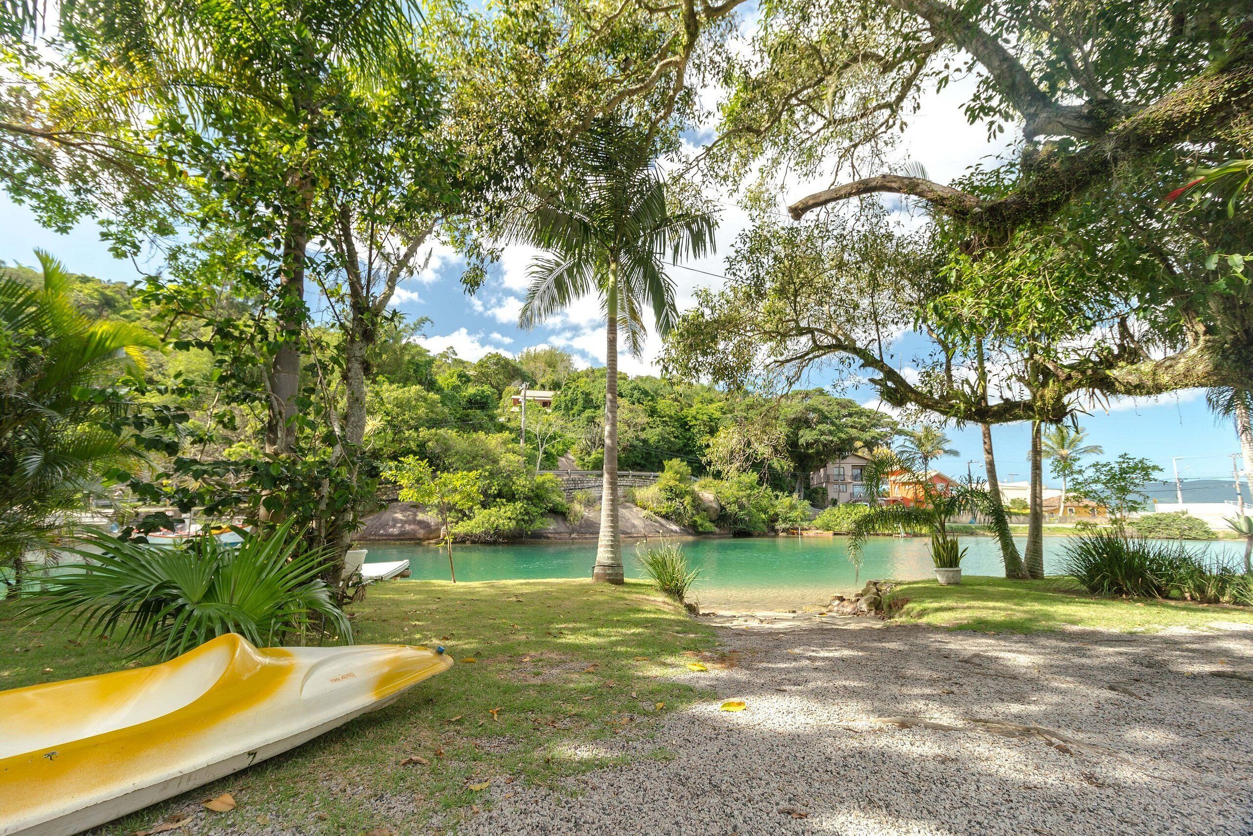 A serene outdoor area with a yellow slide, lush greenery, and a calm body of water.