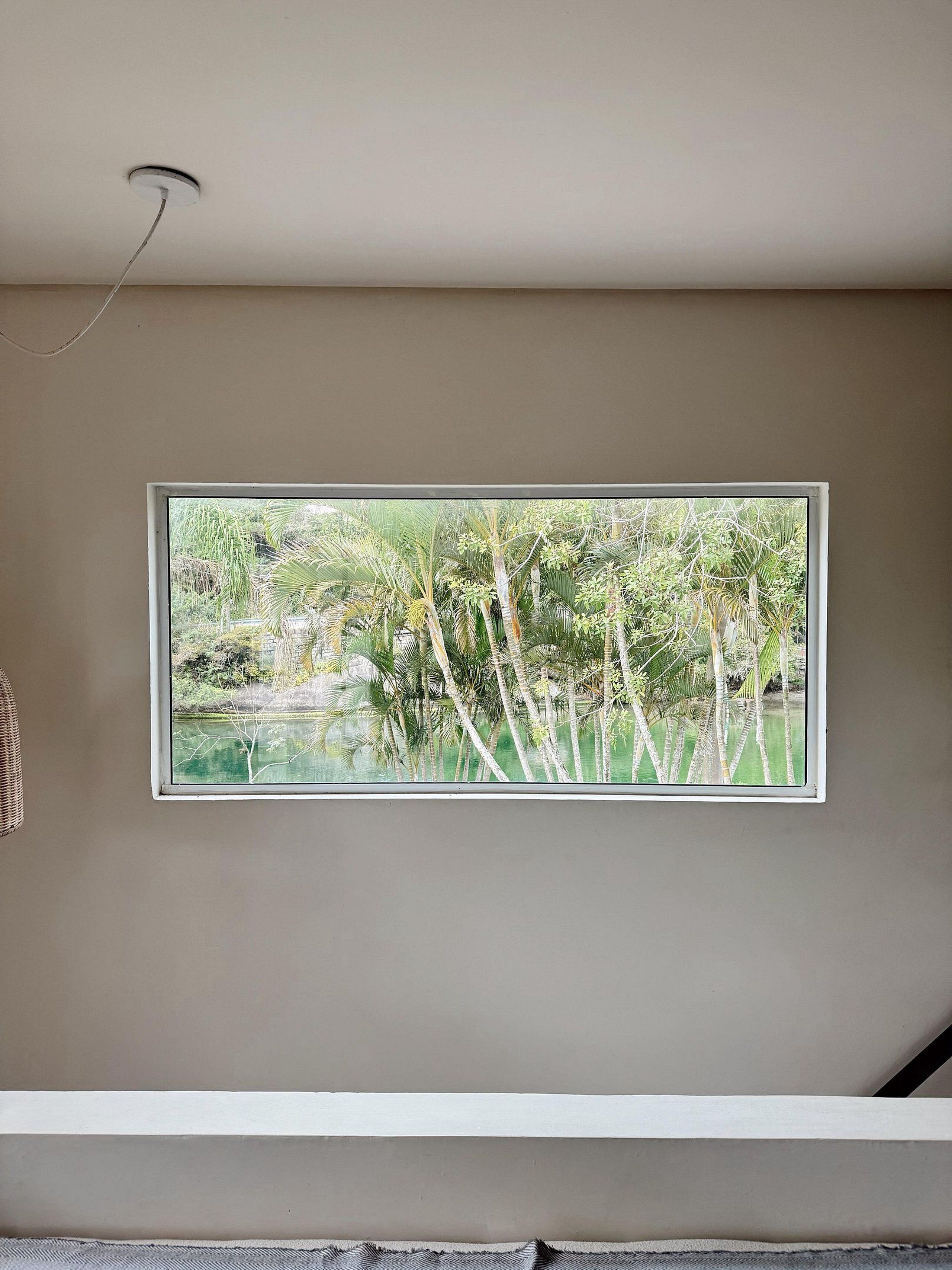 A room with a large window displaying a view of a pond and trees.