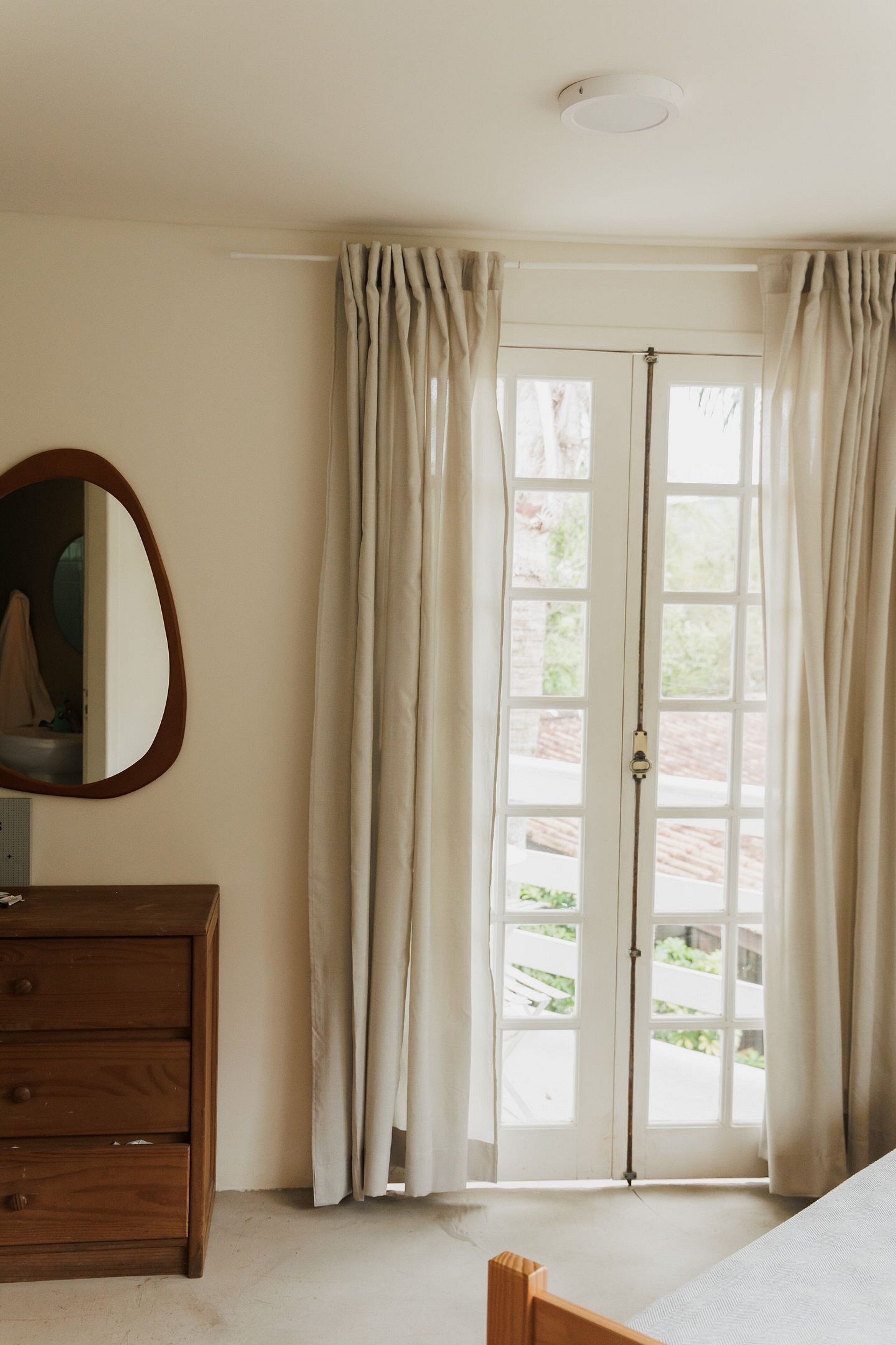 Un dormitorio con un aparador de madera, un espejo y una puerta que da a un espacio exterior.