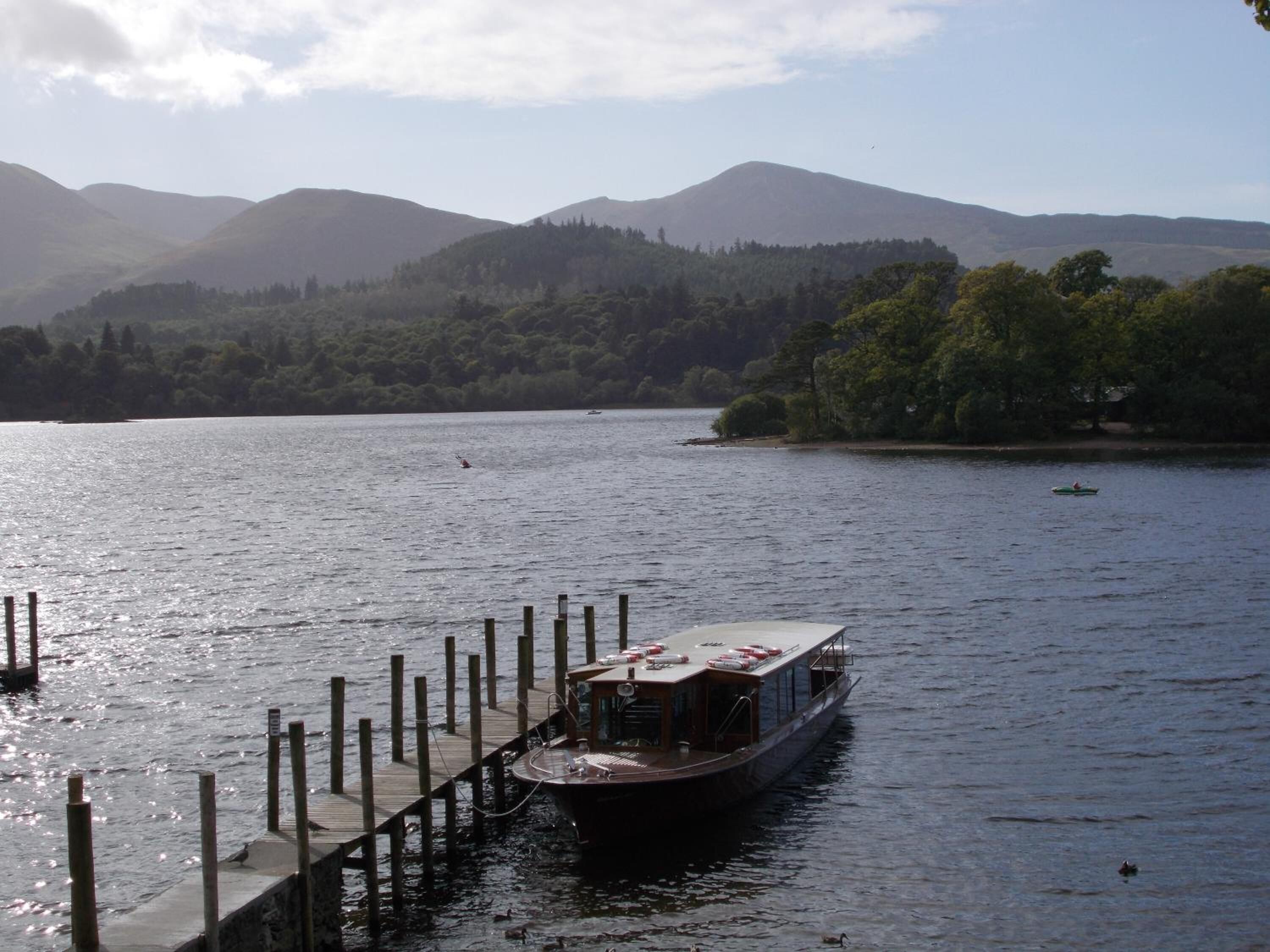 A boat docked at a pier with a mountainous backdrop.