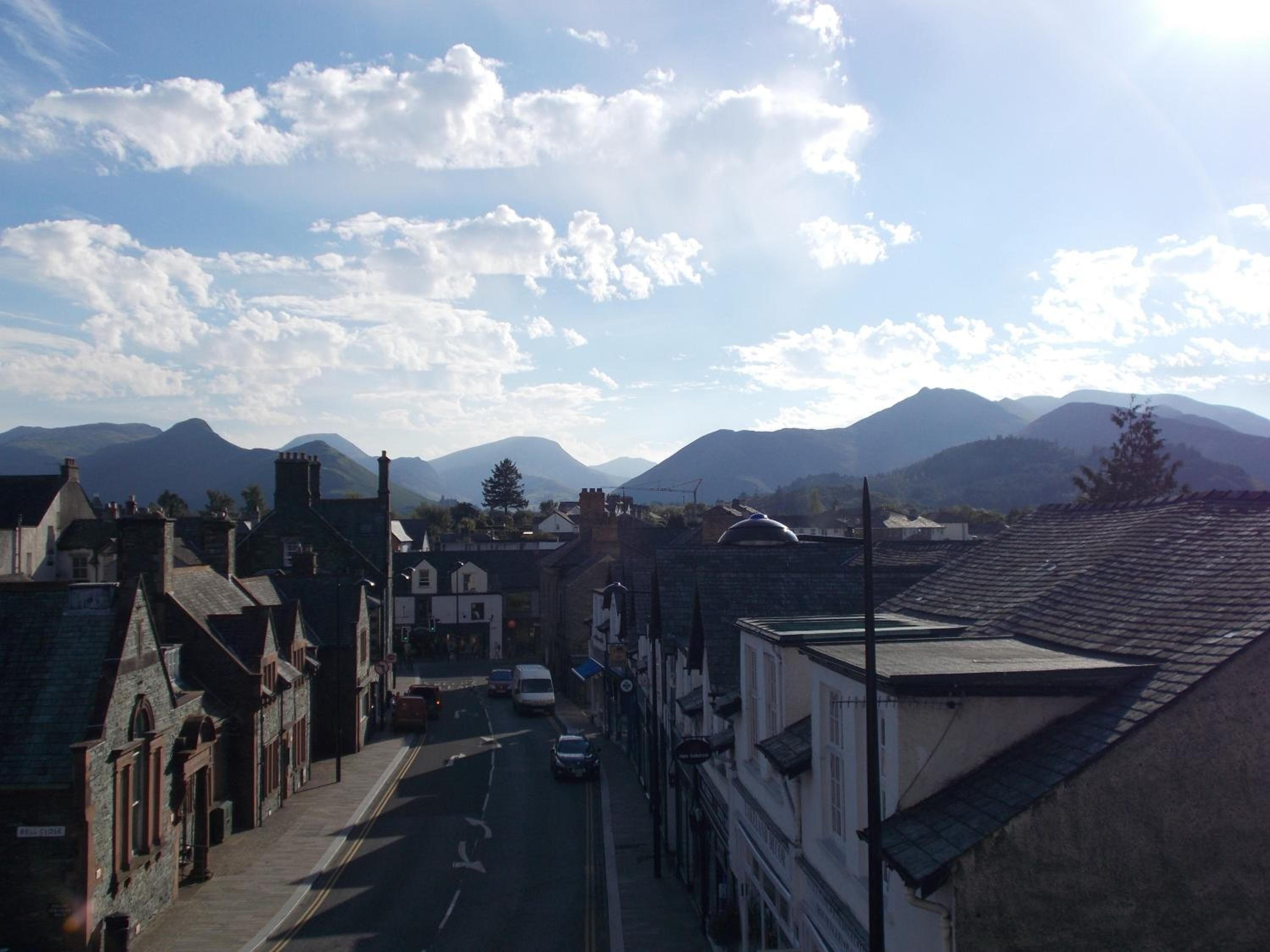 A street view with buildings, a road, and mountains in the background.