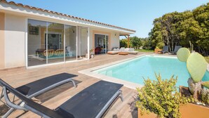 Una casa moderna con piscina, zona de estar exterior y jardín con cactus.