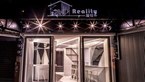 A modern building with a glass facade, a sign reading "Reality," and a staircase leading to an interior space. - Reality Design Inn (Tainan)