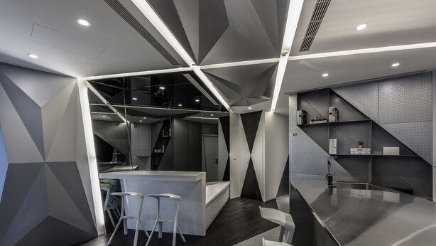 A modern kitchen with a central island, bar stools, and a built-in refrigerator. - Reality Design Inn (Tainan)