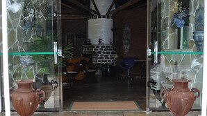 Una entrada con suelo de piedra, una puerta de cristal, un felpudo y dos grandes jarrones.