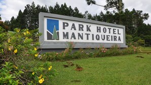 Señal para el Hotel Park Mantiquitoira con un logotipo, rodeado de vegetación y flores.