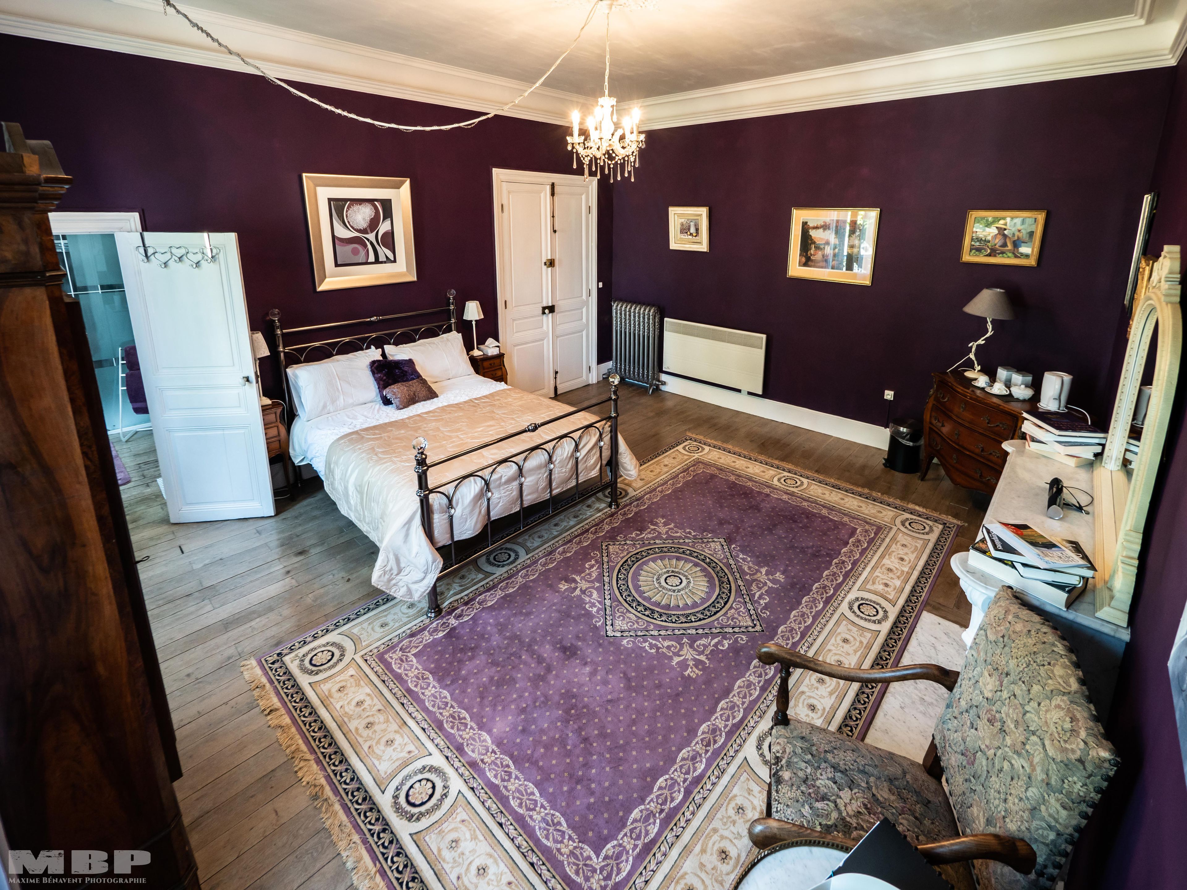 A bedroom with a large bed, a dresser, a chair, and a rug.