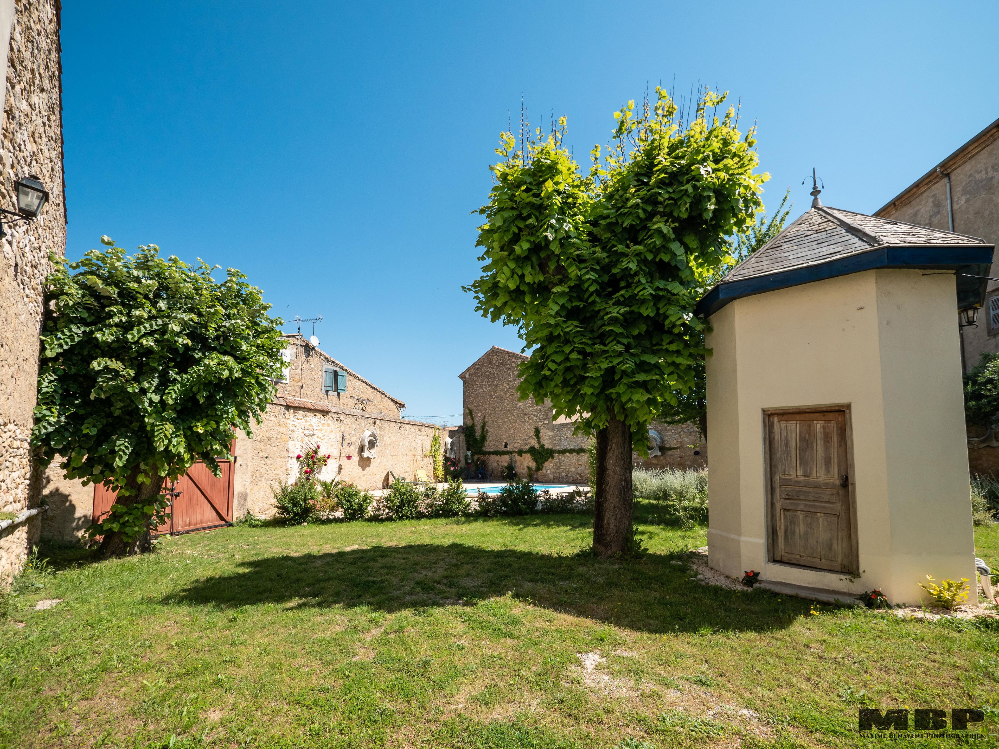 A courtyard with stone buildings, a small tree, and a wooden door.