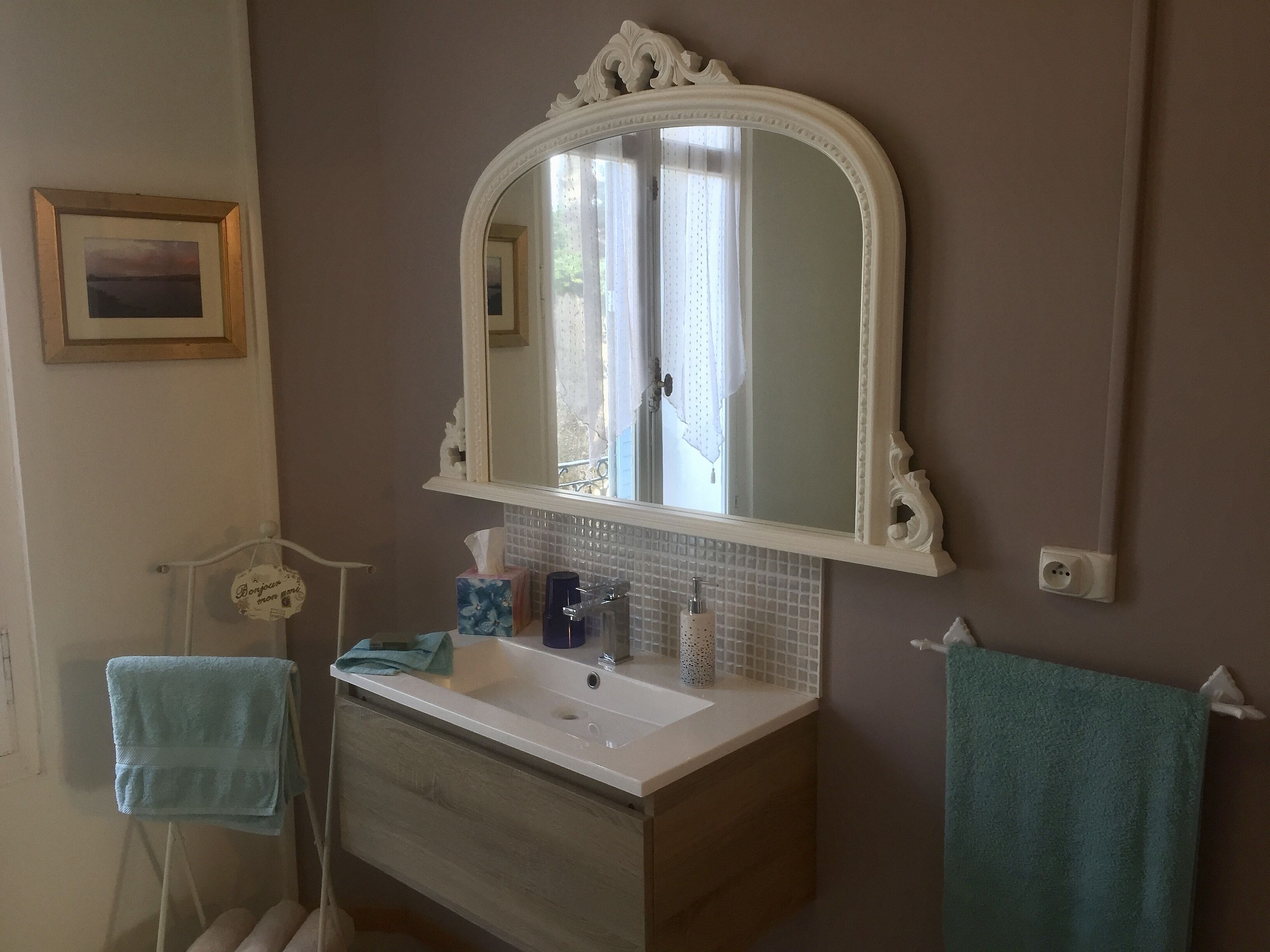 Een badkamer met een wit aanrichtmeubel, een grote spiegel en een handdoekhouder.