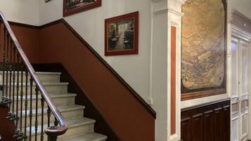 A staircase with wooden balusters and a marble wall with a large painting.