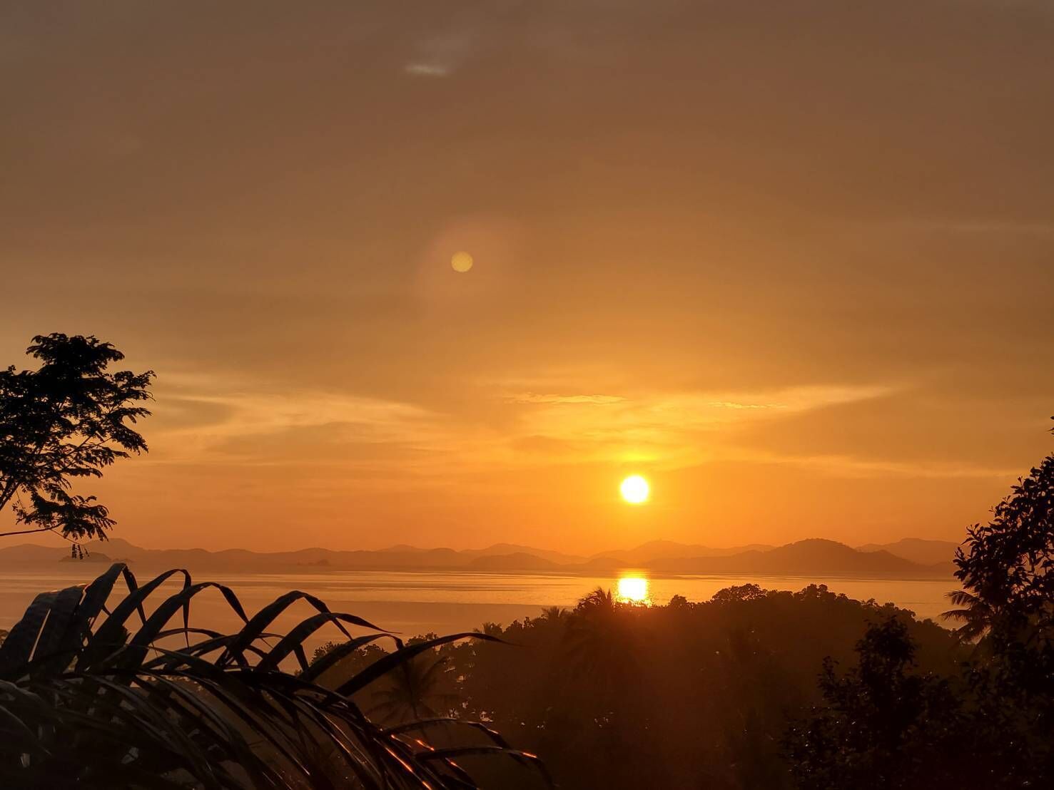 A sunset over a body of water with mountains in the background.