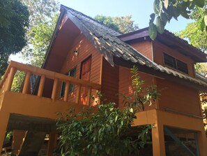 Una casa de fusta de dos pisos amb un balcó, una finestra i una porta.