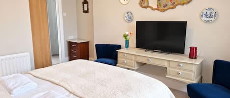 A bedroom with a bed, a TV, a dresser, and a chair.