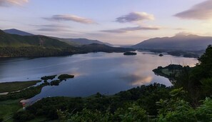 A panoramic view of a lake surrounded by mountains and lush greenery.