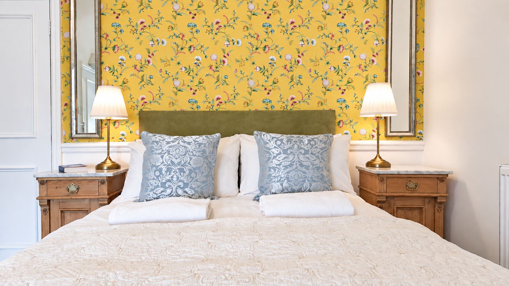 Une chambre d’hôtel avec un grand lit, deux tables de chevet et un miroir au-dessus du lit.