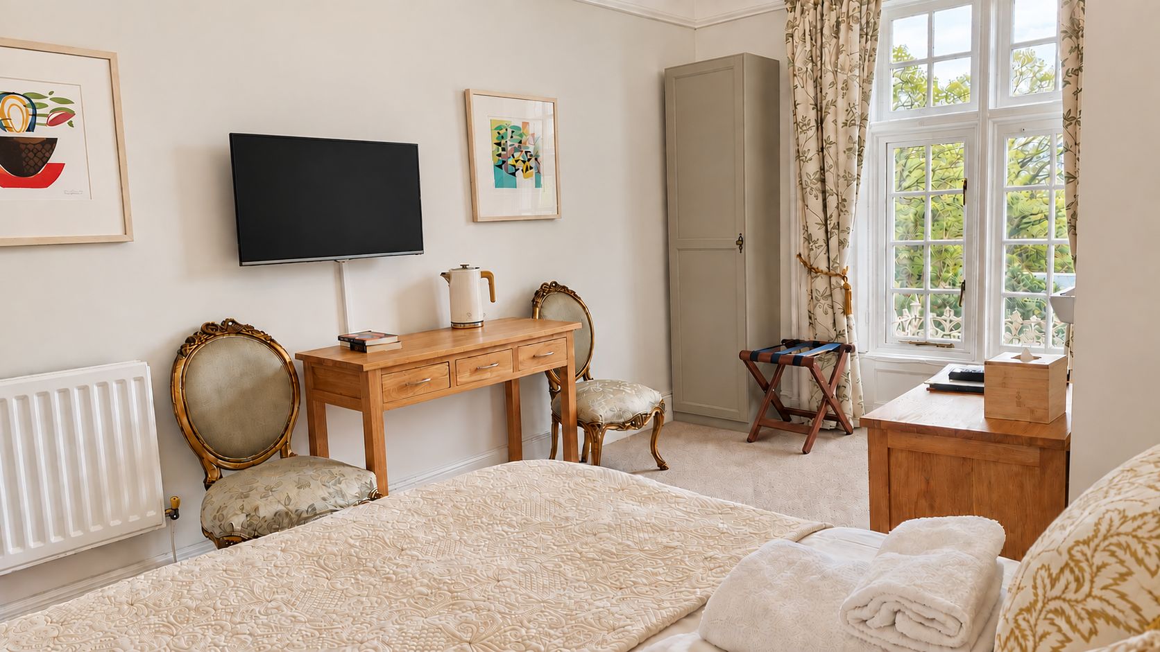 A bedroom with a bed, a desk, a chair, a television, and a wardrobe.