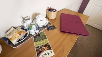 A table with a tray of food, a menu, a coffee cup, a basket of pens, and a red folder labeled "Guest Information".