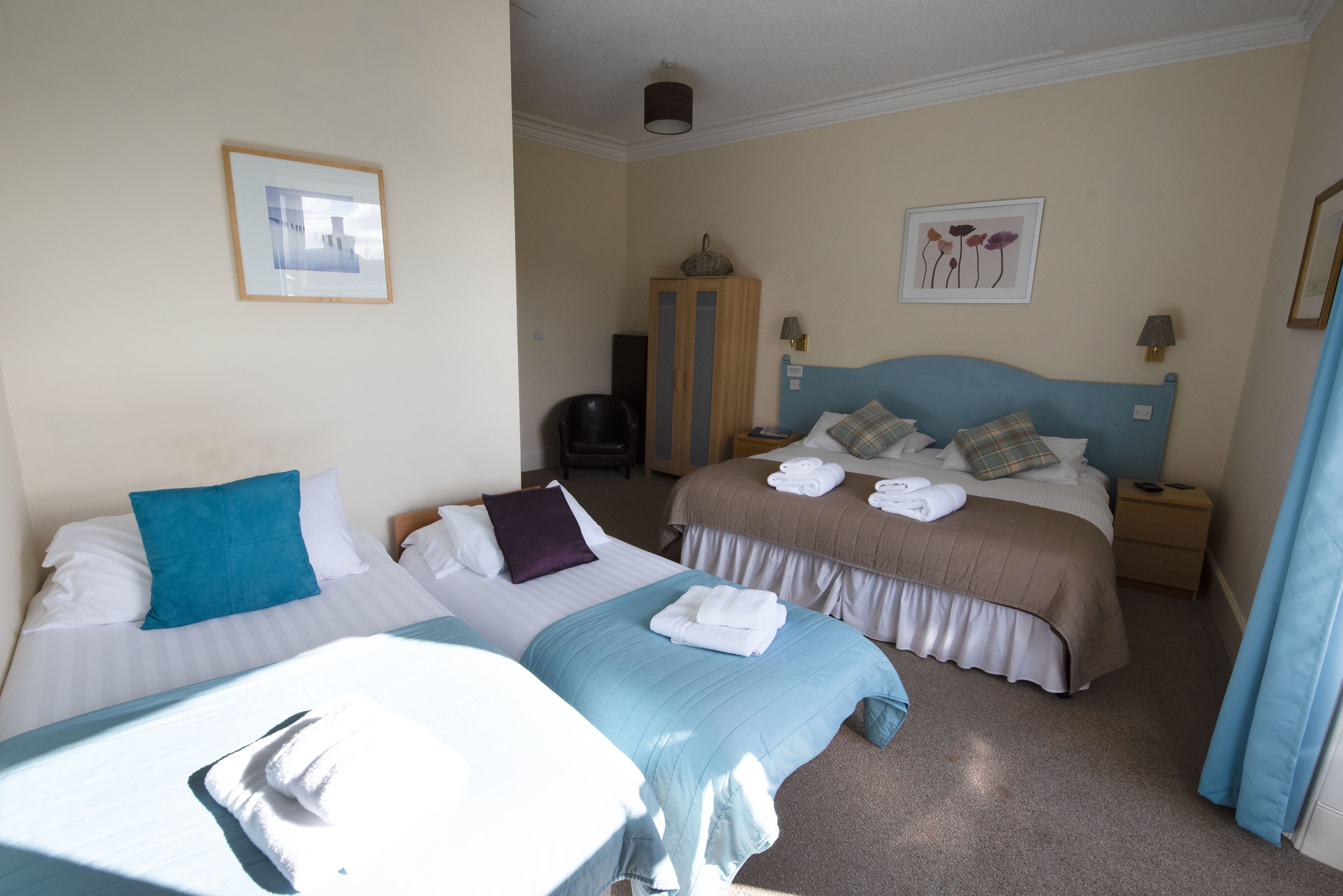 A hotel room with two beds, a desk, and a wardrobe.