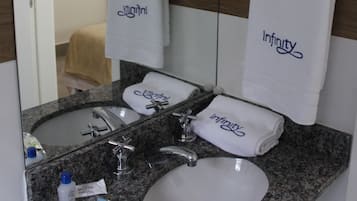 A bathroom with a granite countertop, two sinks, a mirror, and towels with the word "Infinity".