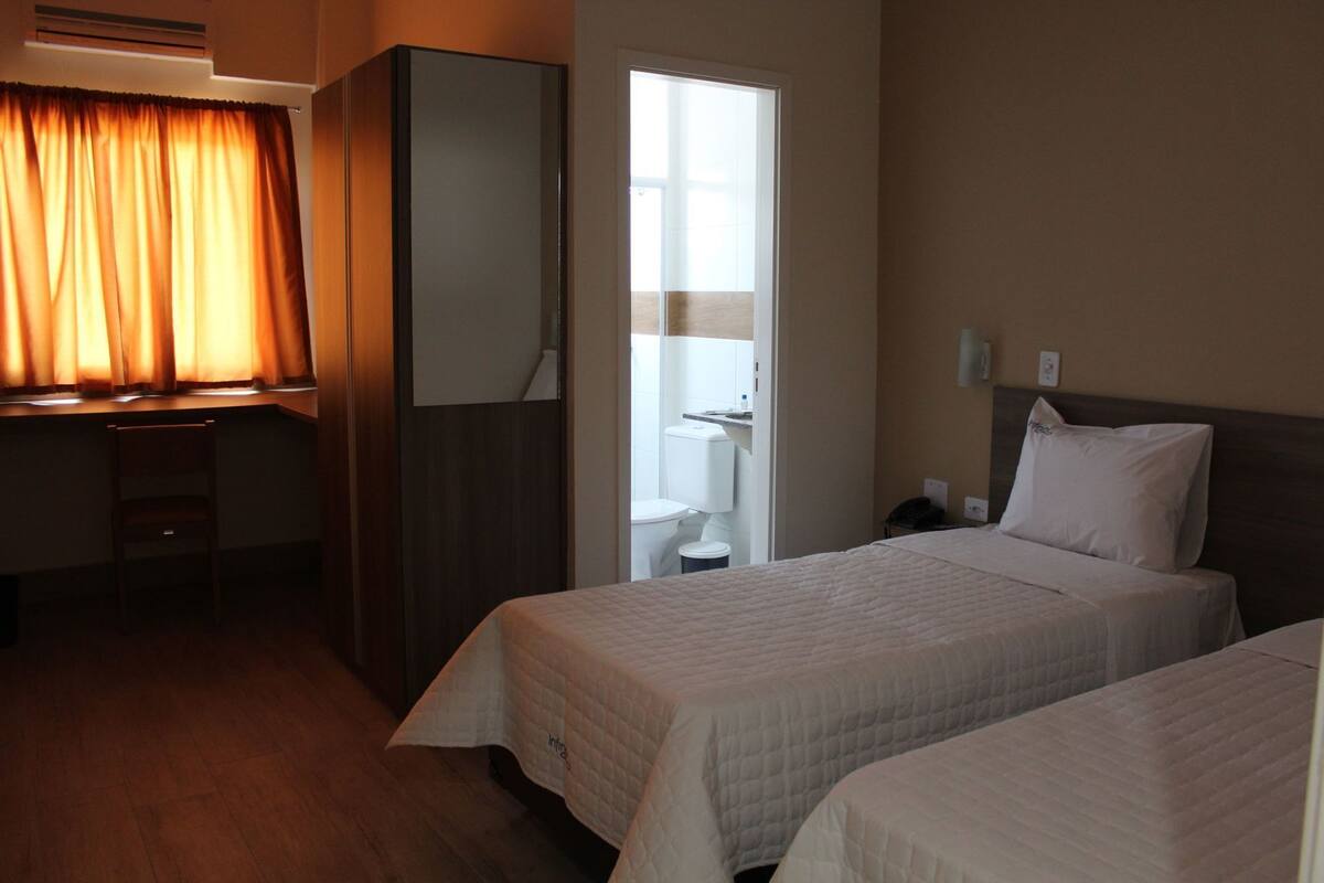 Une chambre d’hôtel avec deux lits, un bureau, une armoire et une salle de bain.