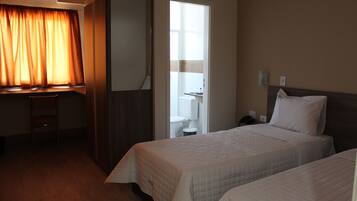 A hotel room with two beds, a desk, and a wardrobe.