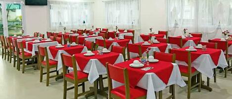 A dining area with tables set for service, chairs, and a television on the wall.