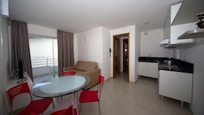 A modern apartment with a dining area, a living room with a sofa, a kitchen, and a balcony. - Caravaggio Residence (Natal)
