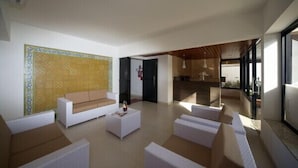 A spacious living area with a white sofa, a coffee table, and a patterned wall. - Caravaggio Residence (Natal)