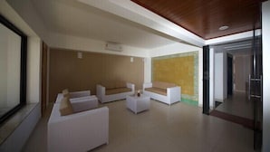 A modern living room with white sofas and a coffee table, a wooden ceiling, and a large window. - Caravaggio Residence (Natal)