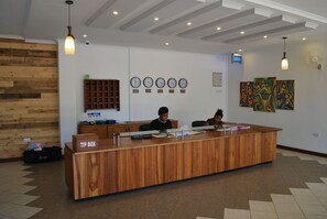 A reception desk with a wooden finish, a tip box, and a wall-mounted clock.