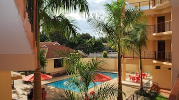 Un patio con piscina, palmeras y mobiliario de exterior.