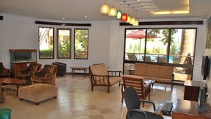 A spacious room with multiple seating options, including sofas and chairs, a desk with a computer, and a fish tank. - Parkview Inn (Moshi)