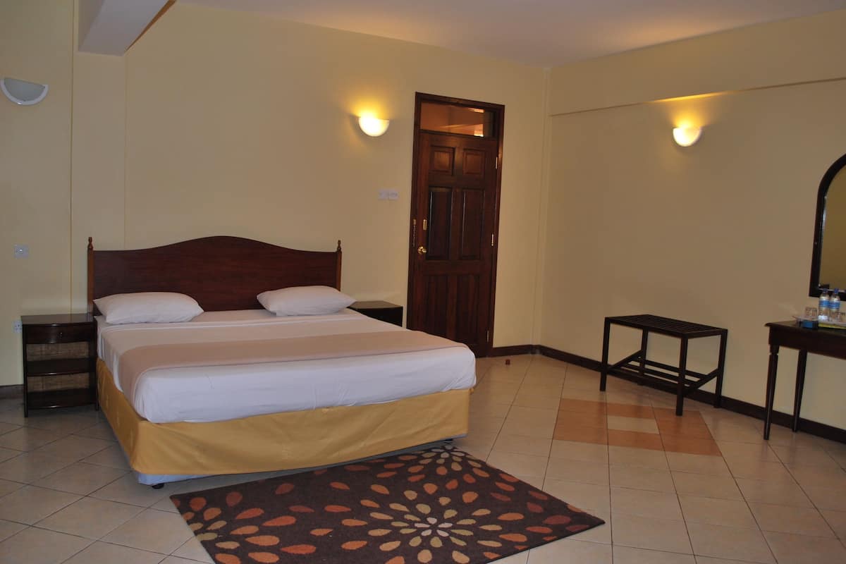 A bedroom with a bed, bedside tables, a door, and wall-mounted lights.