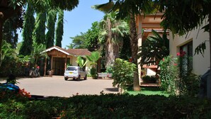 A residential area with a white car parked in front of a house, surrounded by lush greenery and palm trees. - Parkview Inn (Moshi)