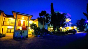A two-story building with a well-lit entrance and a car parked in front. - Parkview Inn (Moshi)