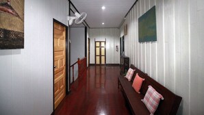 A hallway with a wooden bench, a fan, and a door leading to another room. - OB-ARUN House (Bangkok)