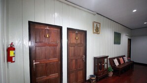 A hallway with two wooden doors, a fire extinguisher, a bench, and a small cabinet. - OB-ARUN House (Bangkok)